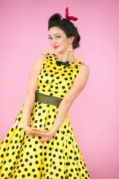 Retro girl. Beautiful woman in a dress with polka dots on a bright background. photo
