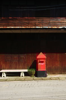Red Postbox on footpath near old wooden house at countryside In Thailand photo