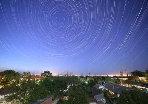 trails of stars in night sky above city photo