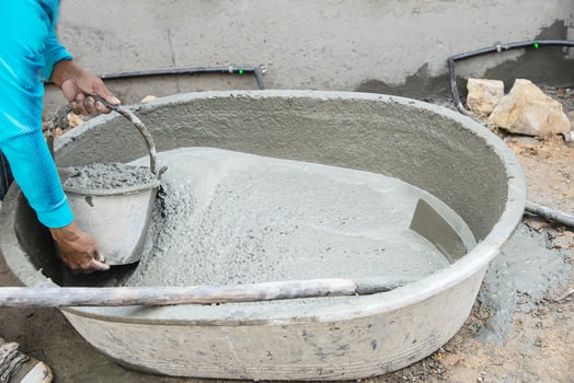 builder contractor man job mix concrete in industry work project, pouring wet liquid material into the big mixing tray in construction site as professional employment photo