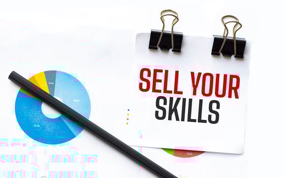 Notepad with text sell your skills on business charts and pen photo