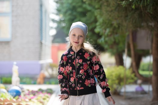 A cheerful little preschooler girl plays on a spring street. photo