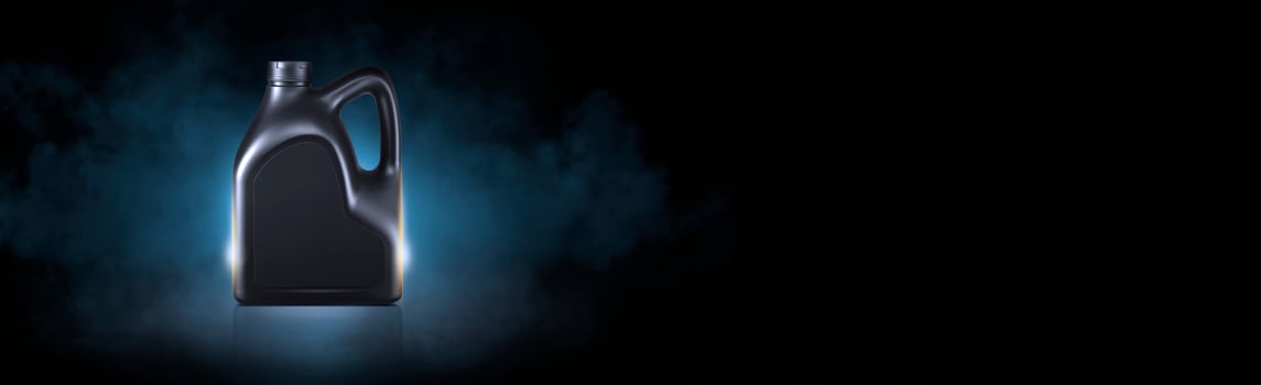 Black bottle of engine oil on black background with smoke photo