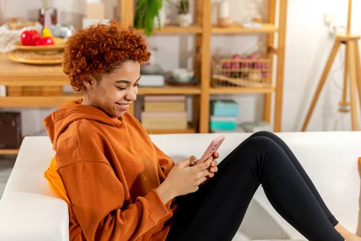 African girl holding smartphone touch screen typing scroll page at home. Woman with cell phone surfing internet using social media apps playing game. Shopping online Internet news cellphone addiction. photo