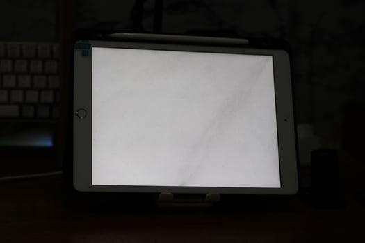 Photo of an empty tablet with white screen on the table