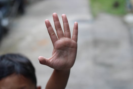 photo of hand waving outside the street
