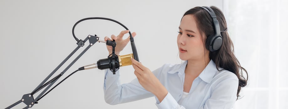 Beautiful asian young woman radio host working, setting microphone, preparing to speak before recording podcast and live on social media. Technology of on-air online in broadcasting at home studio. photo
