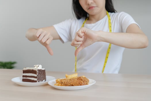 Diet, Dieting unhealthy asian young woman, girl hand in deny, rejecting chocolate cake or sweet taste and fried chicken, french fries or junk food. Nutritionist of healthy, nutrition of weight loss. photo