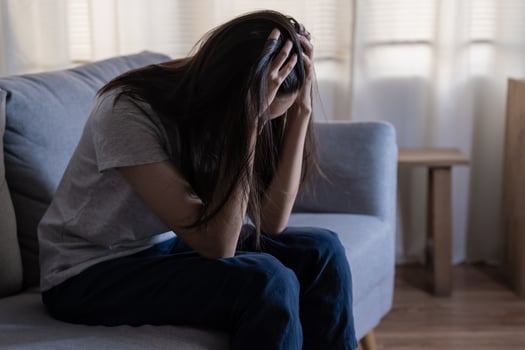 Mental health, depressed sad asian young woman, girl sitting on sofa, couch, expression to face difficulty, failure and exhausted. Thoughtful worried suffering depression feeling lonely, alone at home photo