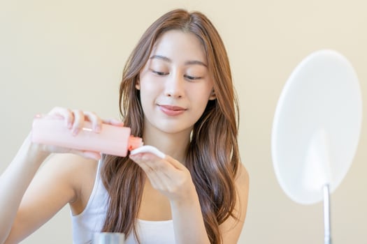 Happy beauty, beautiful asian young woman, girl looking in to mirror, holding cotton pad, applying facial wipe on her face, removing makeup before shower in bathroom, skin care on white background. photo