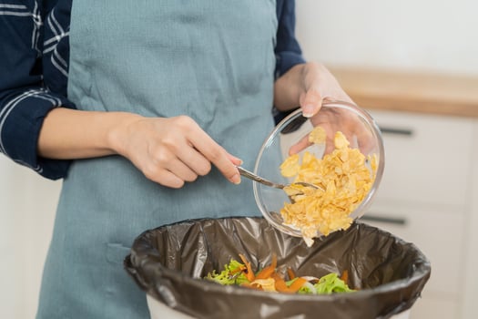 Compost the kitchen waste, recycling, organic meal asian young household woman scraping, throwing food leftovers into the garbage, trash bin from vegetable. Environmentally responsible, ecology. photo