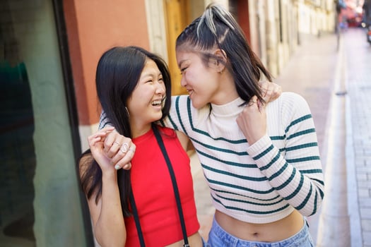Cheerful Asian girlfriends walking on street photo