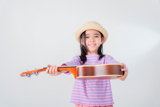 Cute little girl in swimsuit playing ukulele. Happy vacation concept. photo