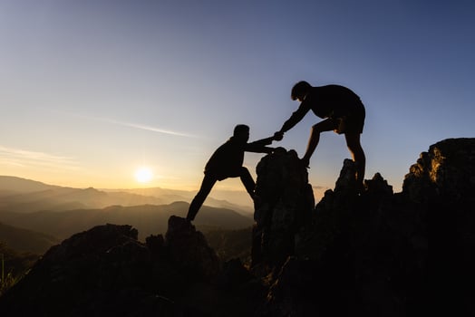 Silhouette Teamwork, Male hikers climbing up mountain cliff and one of them giving helping hand. People helping and, team work concept. photo