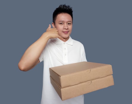 Man holding cardboard box with hand gesture making phone call. photo