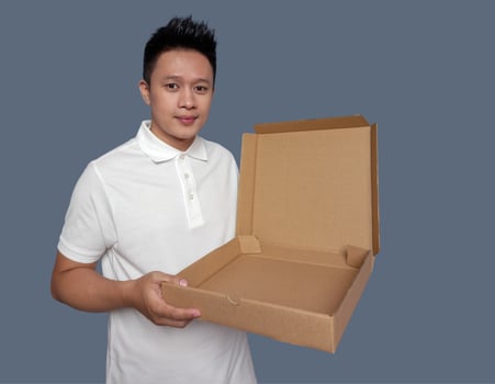 Man holding and opening empty pizza box isolated on plain background. photo