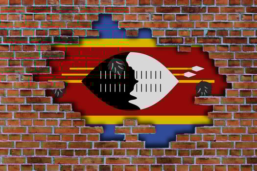 3D Flag of Eswatini behind the broken old stone wall background. photo