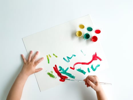 small child draws with paints and brush on white table. fathers day photo