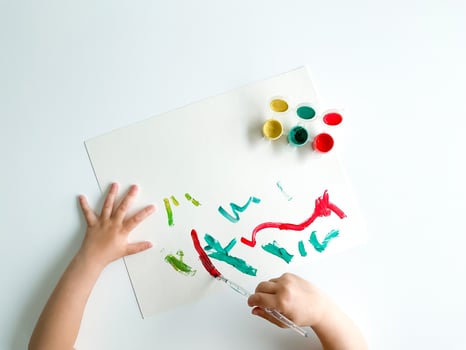 small child draws with paints and brush on white table. fathers day photo