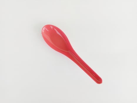 Red plastic spoon on white background photo