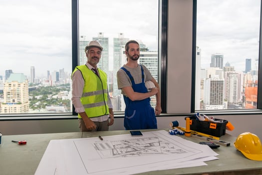 Man engineer standing on construction site, holding blueprints. photo