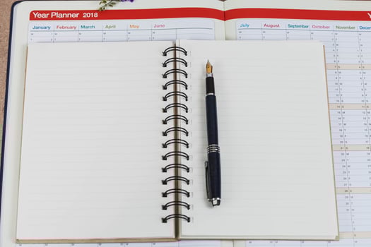 personal organizer or planner with fountain pen on wood table. photo