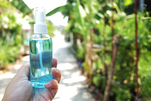 Hand holding a bottle of Ethanol or ethyl alcohol spray for based hand rub is highly effective in reducing influenza a virus on human hands in natural garden. Healthy and Covid19 epidemic Concept. photo