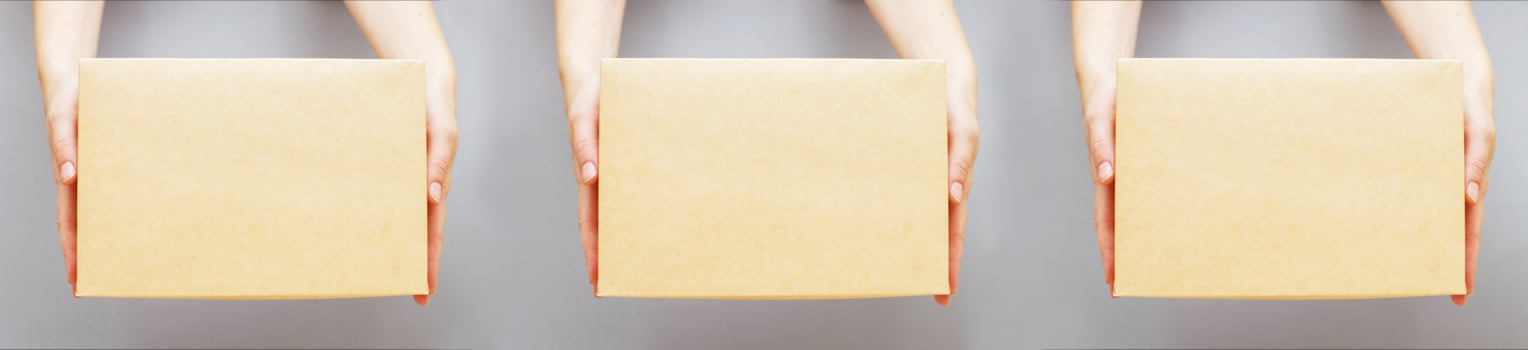human hands holding delivers carton box on grey background. Delivery and online shopping concept. photo