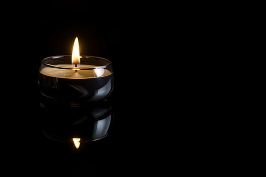 a candle is lit in the dark conveying memorial death and hope with copy space. photo