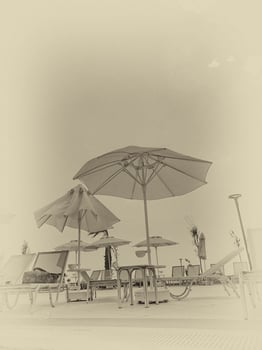 calm landscape over the pool with sunbeds, palm umbrellas and blue cloudless sky photo