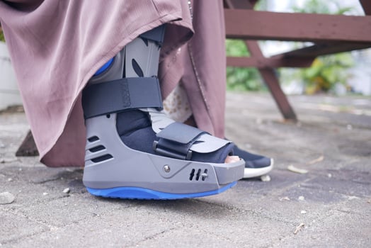women broken feet with a grey plastic boot ankle brace injury protecting boot photo