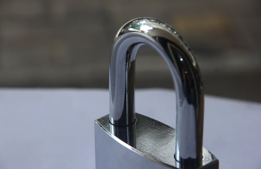Shiny new close up steel metal padlock isolated on white and brick flooring background. photo