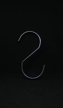 Simple s shaped metal iron stainless steel hook hanger tool object isolated on black background. photo