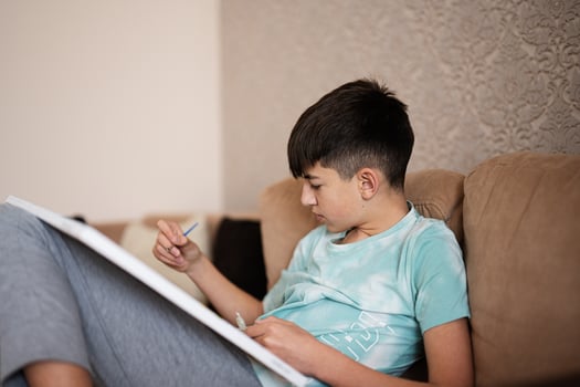 Young male teenager painting picture by numbers on canvas in living room at home. Hobby and leisure concept. photo
