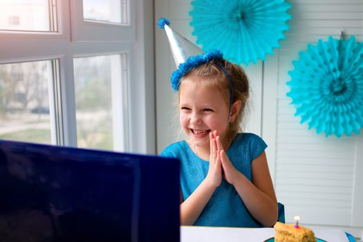 Little happy girl claps her hands, celebrates birthday via the internet in quarantine time, self-isolation and family values, online birthday photo