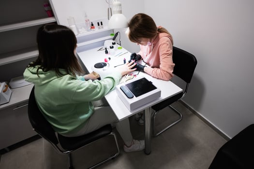 Manicure master working with female client in beauty salon. Manicurist makes woman nail. photo