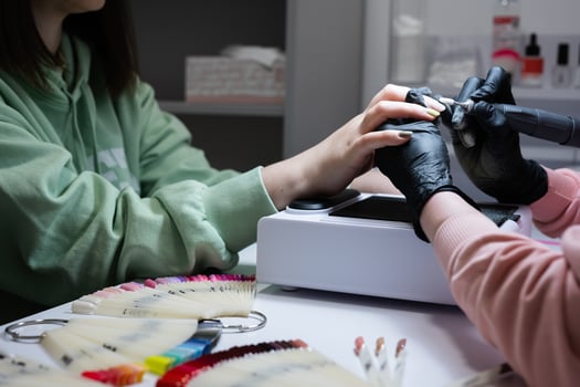Manicure master working with female client in beauty salon. Manicurist makes woman nail. photo