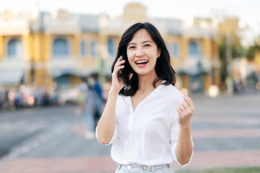 Portrait beautiful young asian woman receiving good news on mobile phone and arms raised feeling cheerful ,happiness. around outdoor street view in a summer day photo