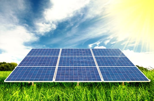 Solar panels on a green field with blue sky photo
