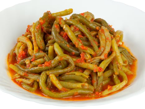 A bowl of green beans with sauce on top photo
