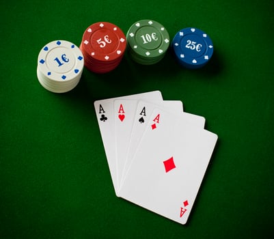 A poker chip, four cards and two chips on a green table photo