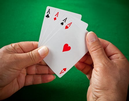 A hand holding four cards on a green table photo