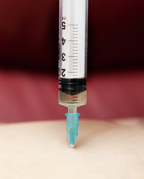 A syringe being used to inject a person photo