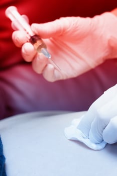 A person in a white glove is holding a syringe photo