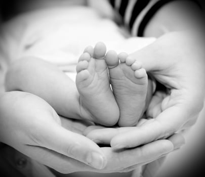 Small feet baby holds his mother in her hands photo