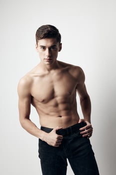 Guy with a naked torso cubes on the stomach sports figure pants model photo