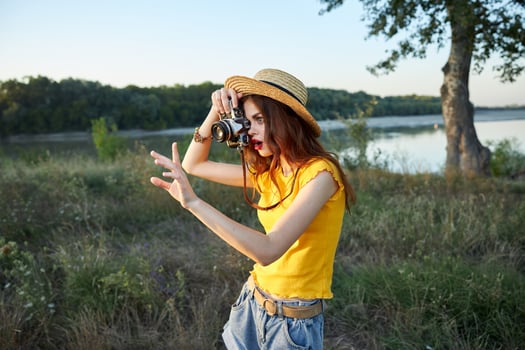 woman photographer wearing hat with camera takes a picture of nature photo