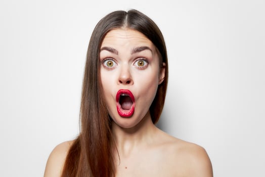 Woman with surprised facial expression wide open mouth bared shoulders long hair photo