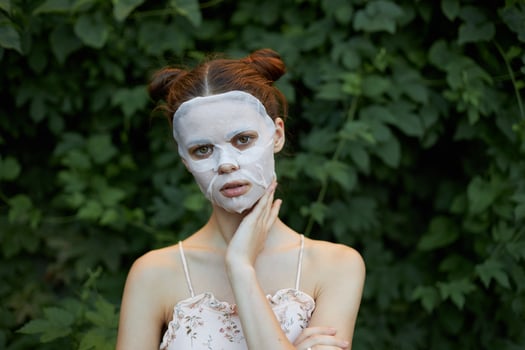 Beautiful woman white mask cosmetology green bushes in the background Copy space photo