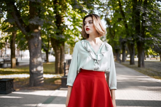 pretty blonde in red skirt outdoors in the park green trees photo